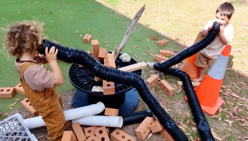 Children building a tunnel with pipes and bricks during loose parts and construction play