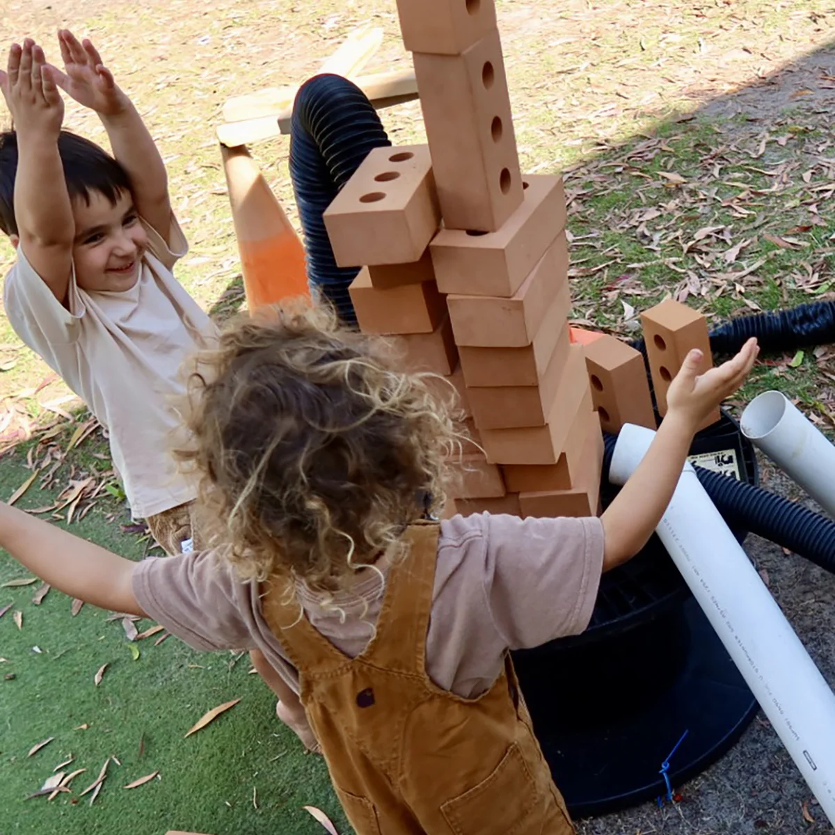 Children building a tower from bricks and tubes during loose parts play