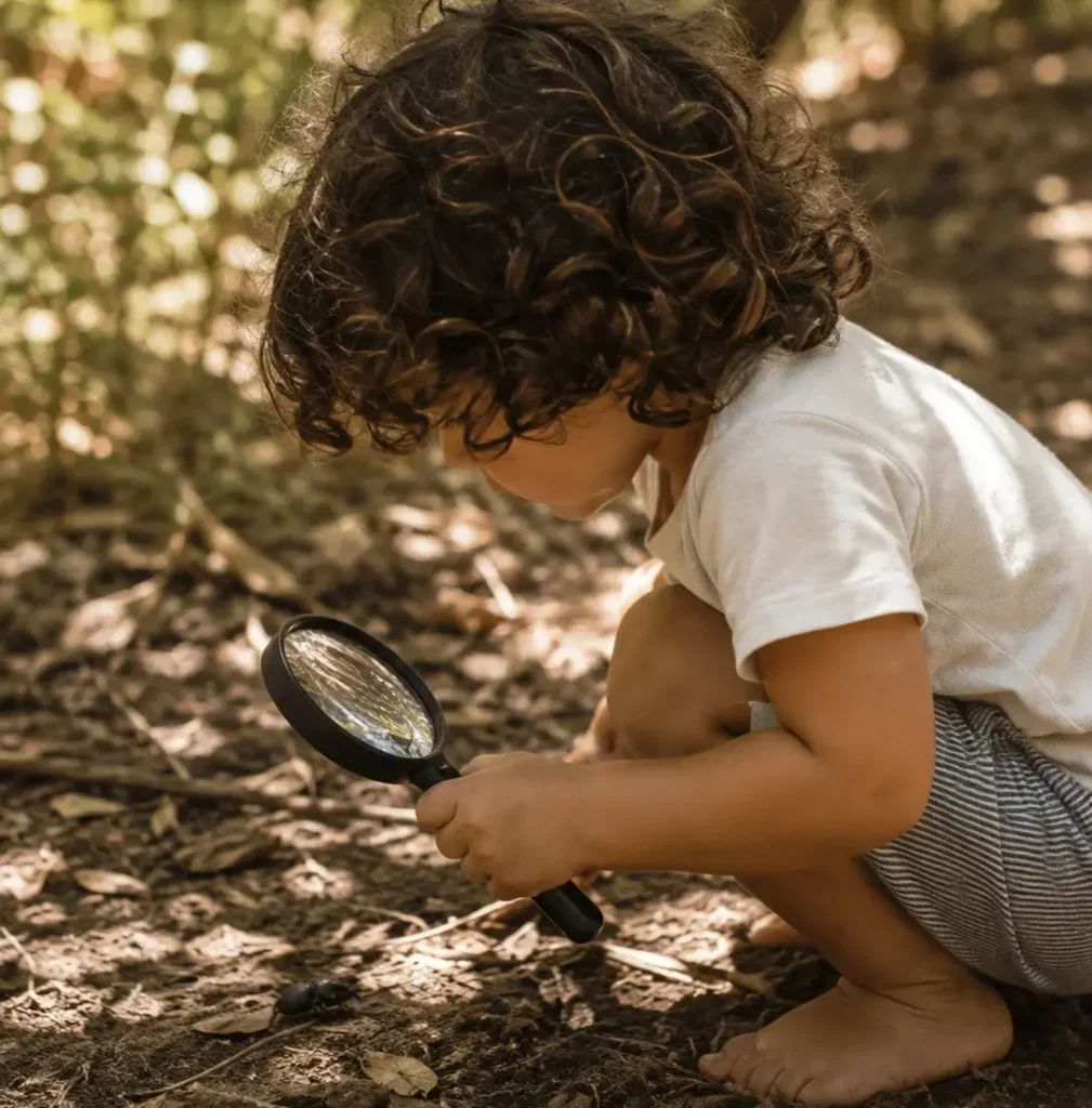 Preschooler with a magnifying glass during curiosity-led early learning at Sunshine Mini School