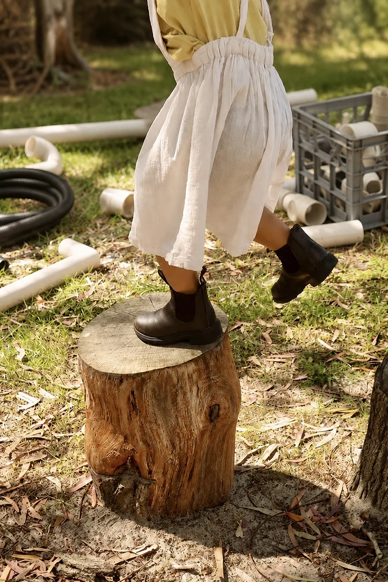 Toddler climbing a tree stump in the natural playground at our Tingalpa childcare centre